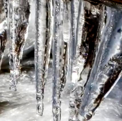 Icicles hang over a chilly flowing creek.