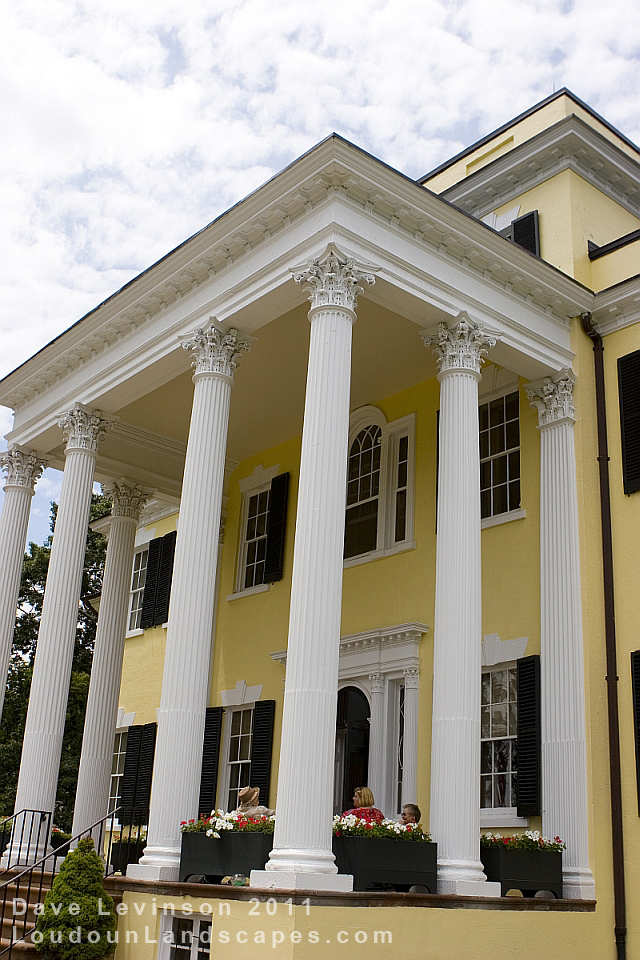 Tall yellow plantation mansion with several white columns.